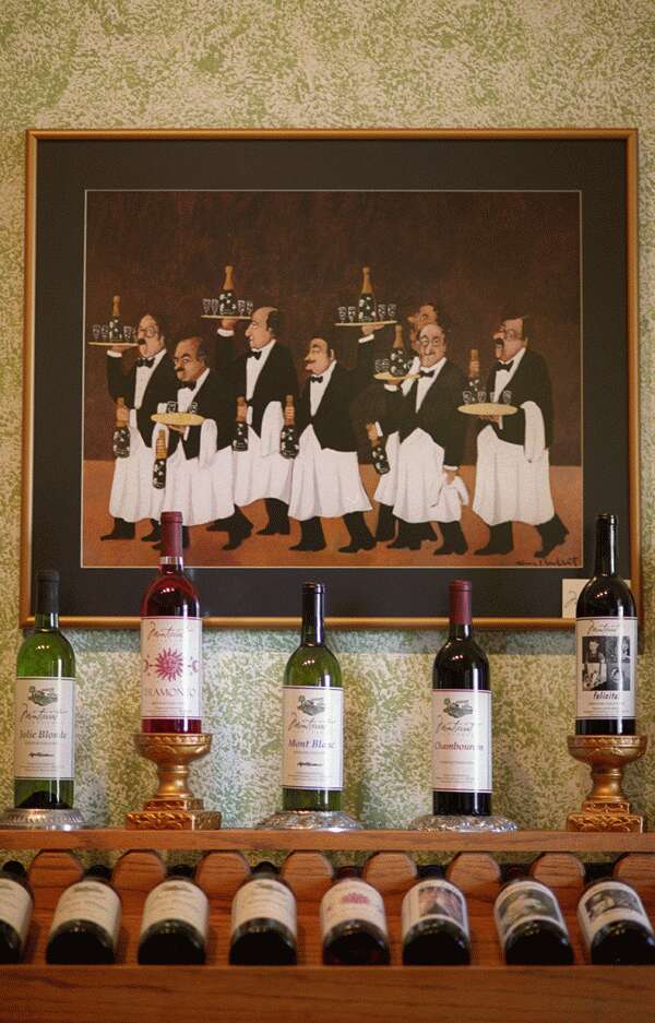 Montserrat Vineyards - indoor photo, a painting of several waiters on a wall above a wine bottle display rack filled with wine bottles.