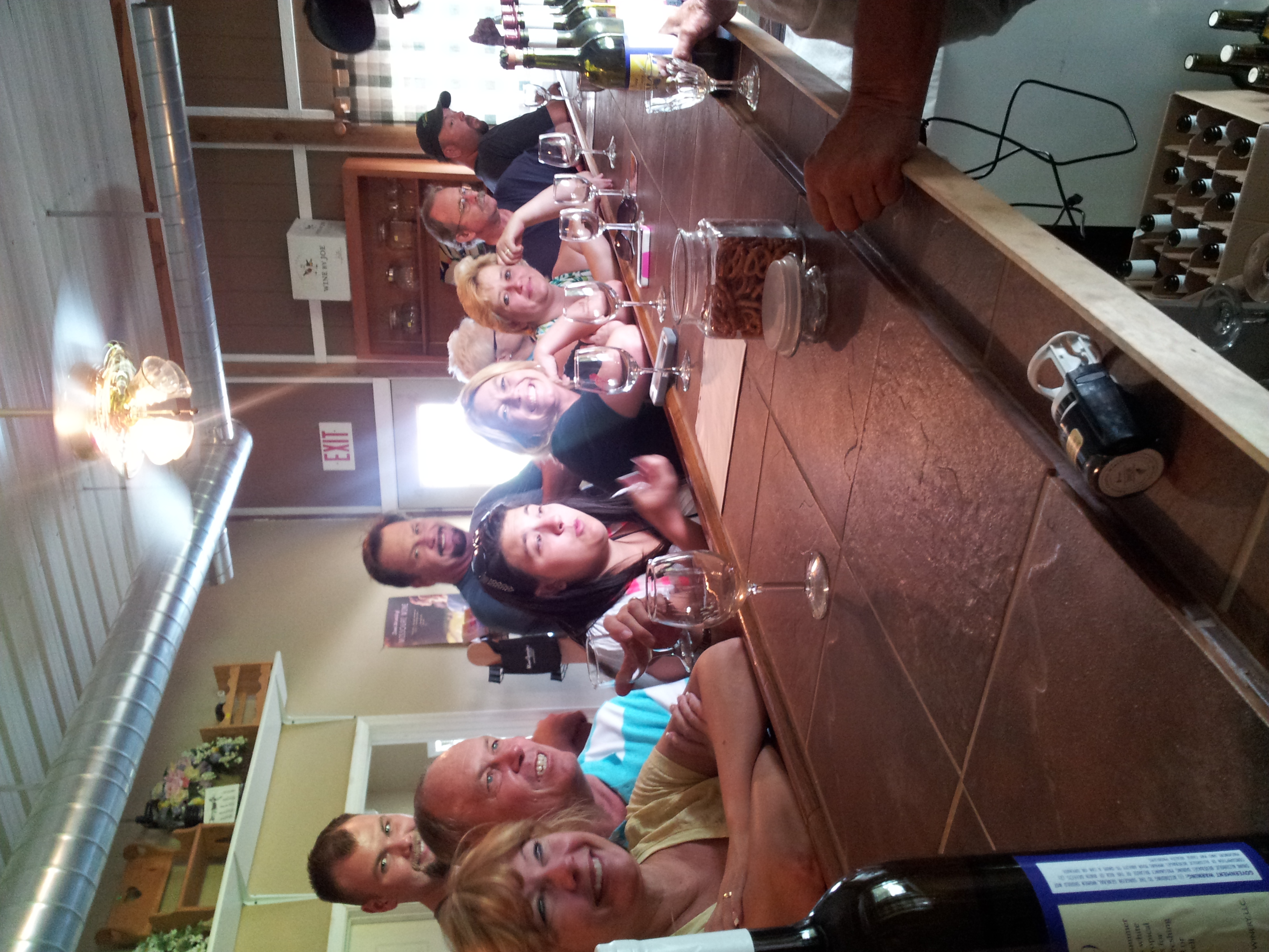 Odessa Country Winery- A group of smiling people sitting at a bar and being served.