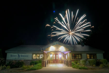Seven Springs Winery - outdoor photo, nighttime, of the exterior of the main winery building. Fireworks are visible in the sky above the building.