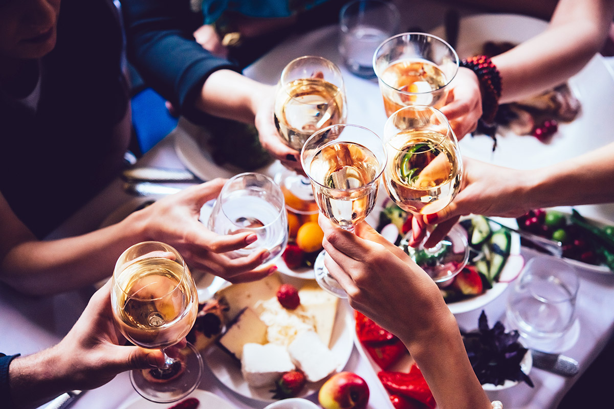 Cheers to Toasting Traditions- Group of friends gathering over a table full of food, toasting