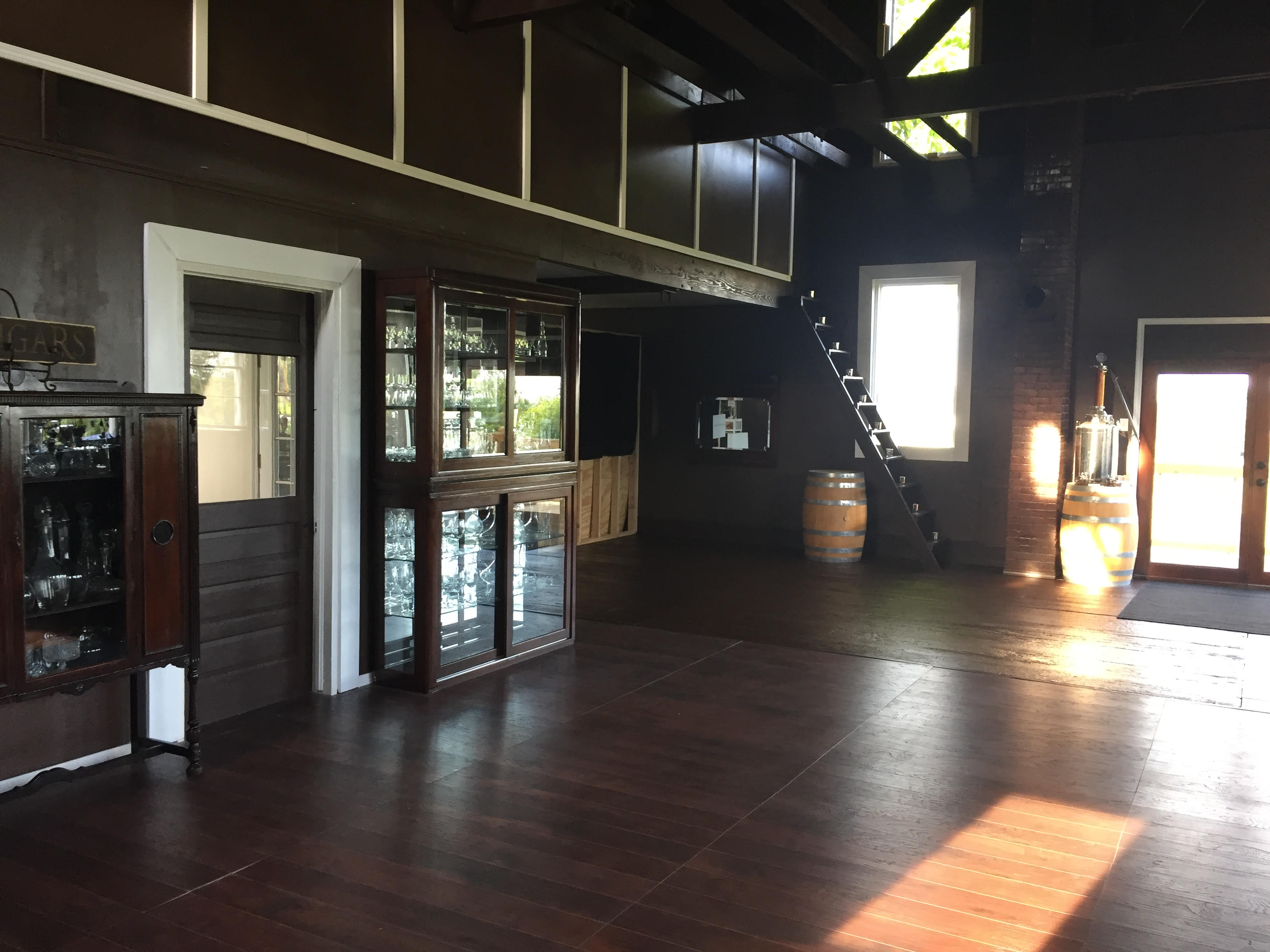 Holy Grail Winery & Vineyard- Brown room with glass cabinets with stairs leading up