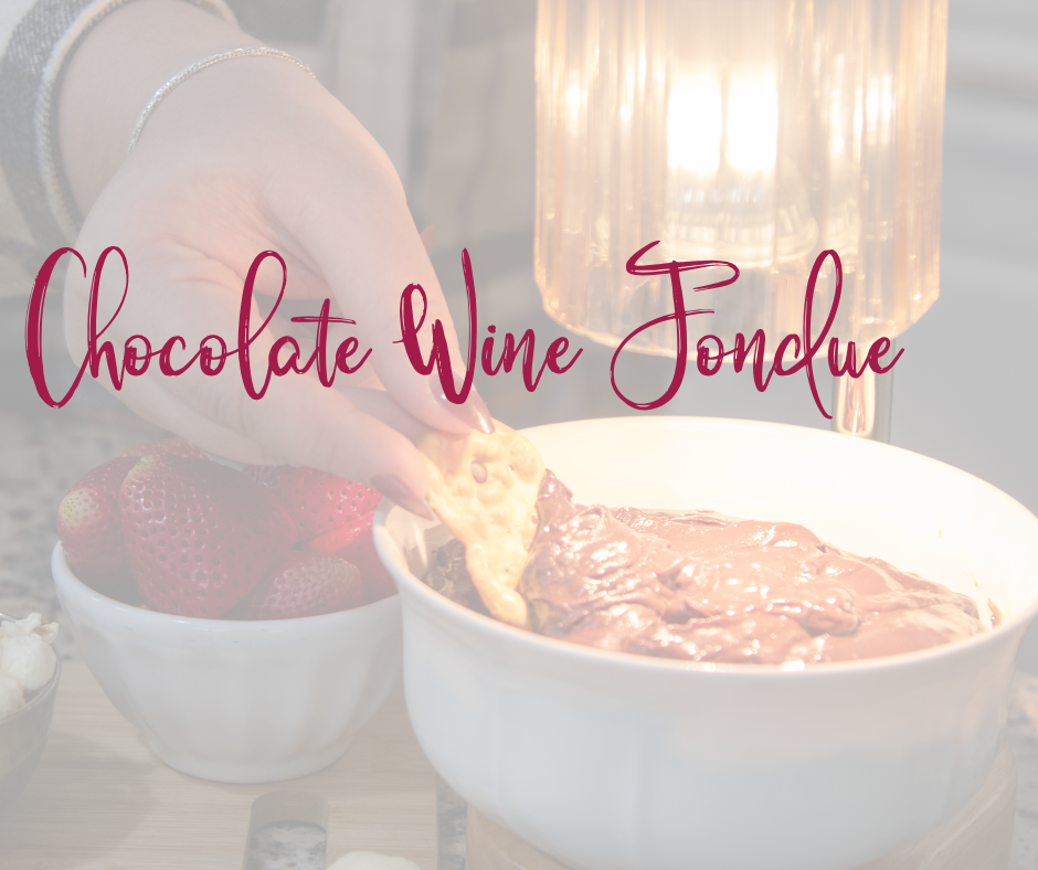 A cutting board with strawberries on it as well as a bowl of chocolate wine fondue under a candle light. 