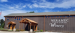Meramec Vineyards Winery - outdoor photo, daytime, of a large grey building with the vineyard's logo on the side.