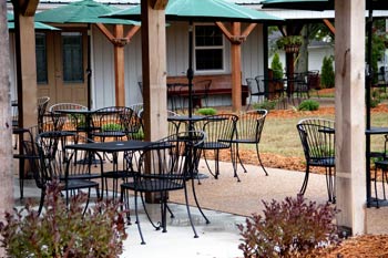 Belmont Vineyards - outdoor photo, daytime, of a patio area with several tables and chairs. Some of the tables have green umbrellas.