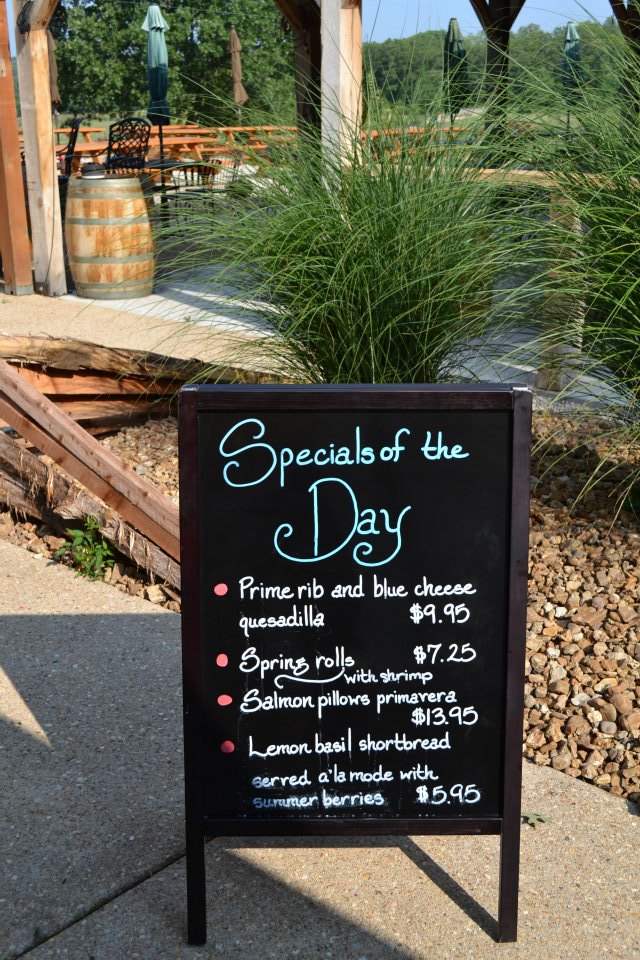 Belmont Vineyards - outdoor photo, daytime, of a chalkboard with meal specials written on it, on a walkway.
