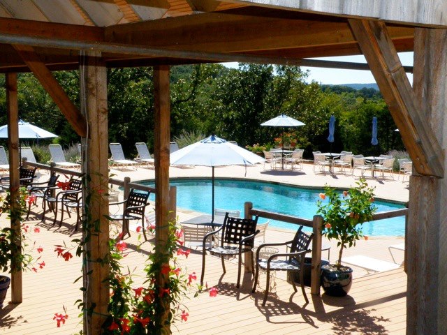 Chaumette Vineyards & Winery - outdoor photo, daytime. A pool area with tables and chairs in the foreground and a pool in the background.