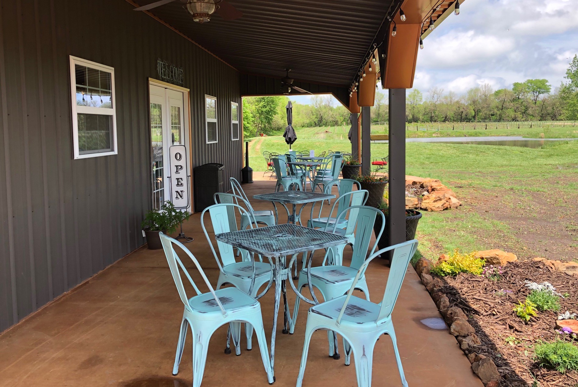 Christine's Vineyard - outdoor photo of a porch with various tables and chairs available for seating, during the day.