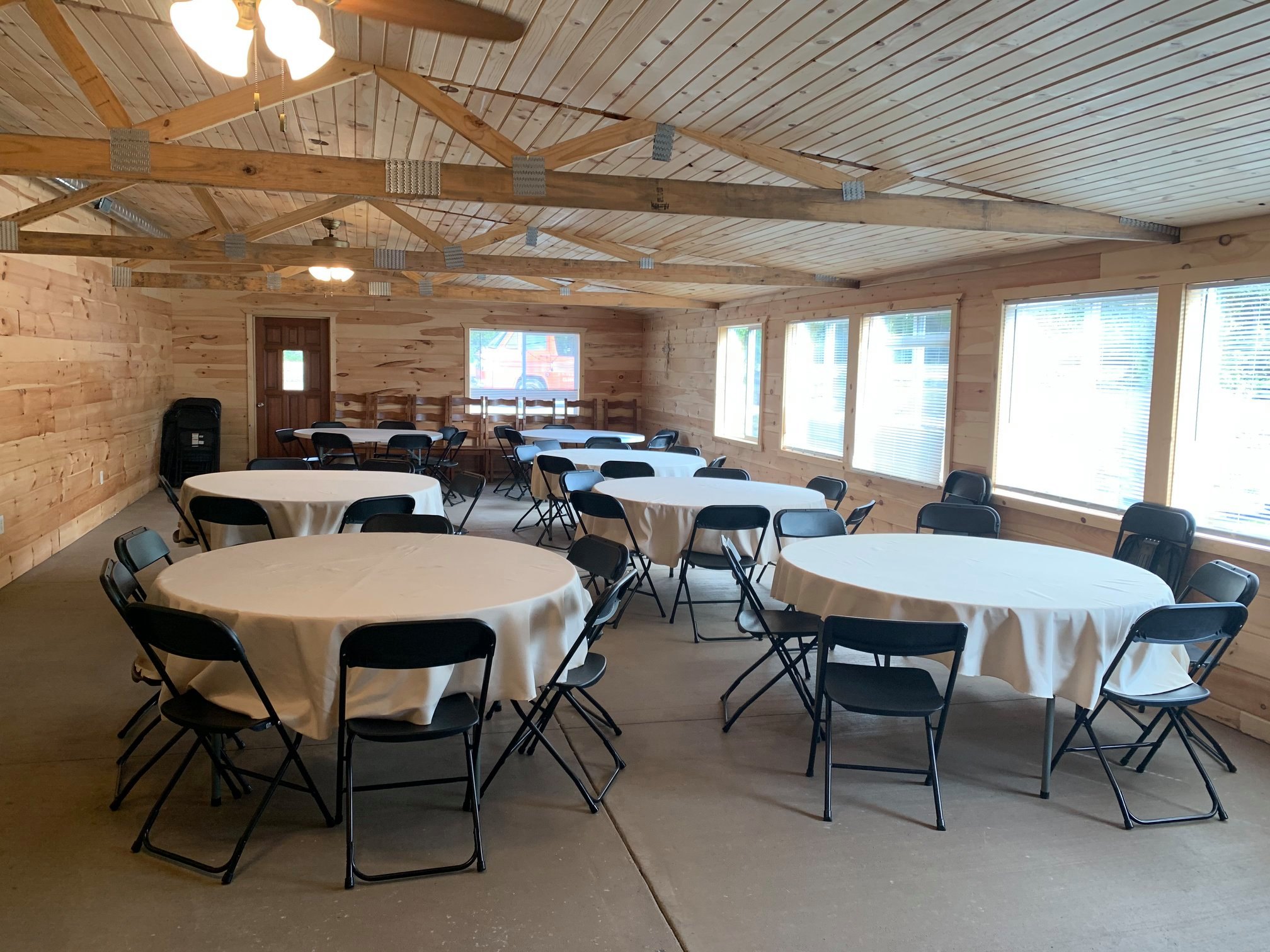 Primitive Olde Crow and Winery- Indoor event room with several windows and tables with white table cloths.
