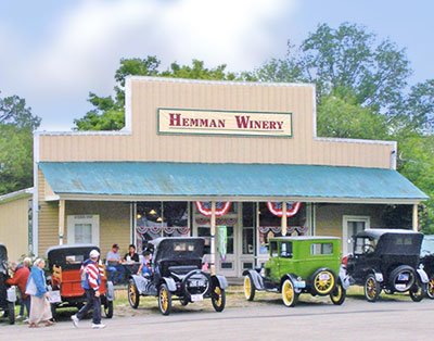 Hemman Winery- Photo of the winery with vintage cars parked in front and a crowd of people walking up.
