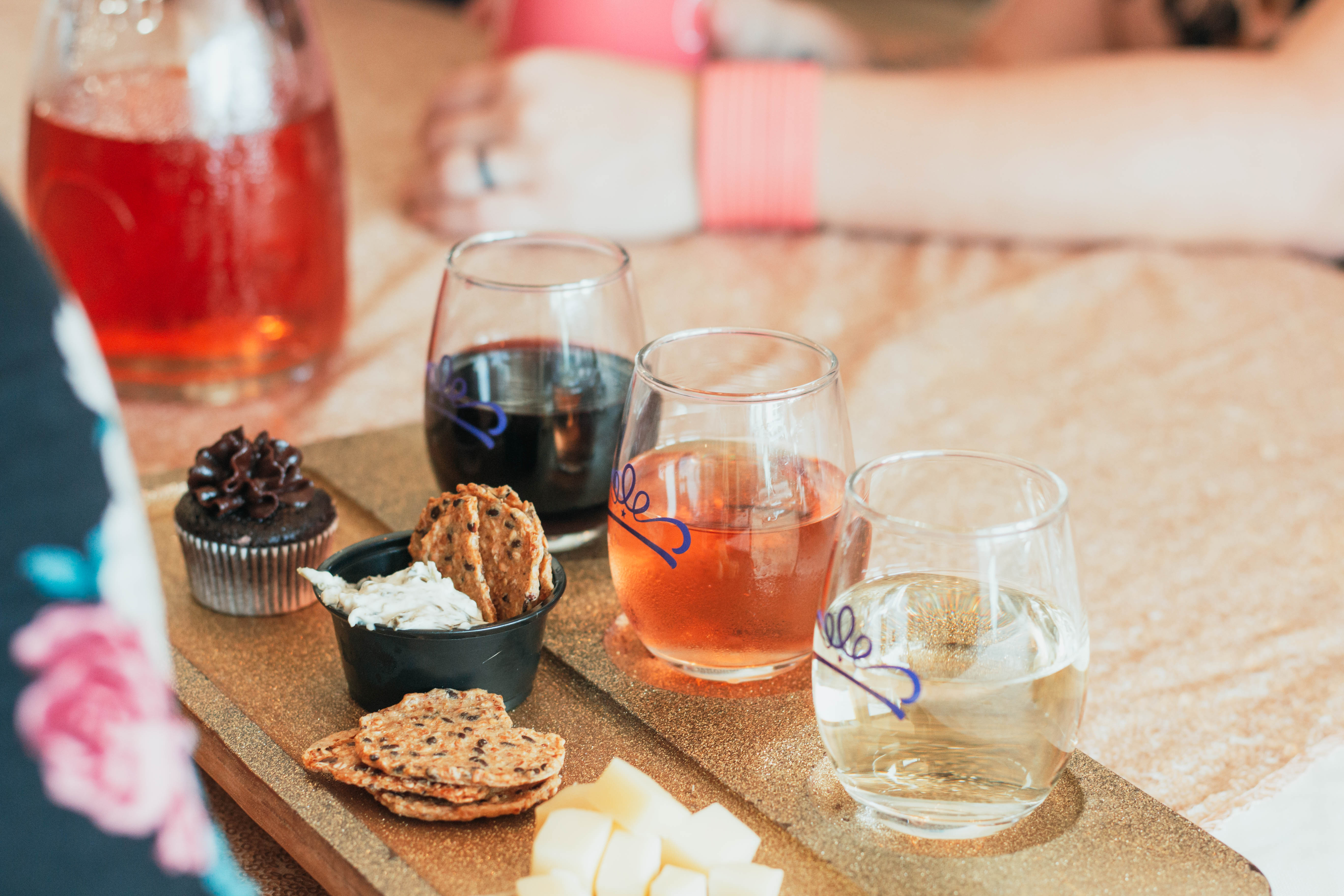 Weston Wine Company- Tray of snacks and three glasses of wine. Including a chocolate cup cake, crackers, cheese, red, white, and pink wine.