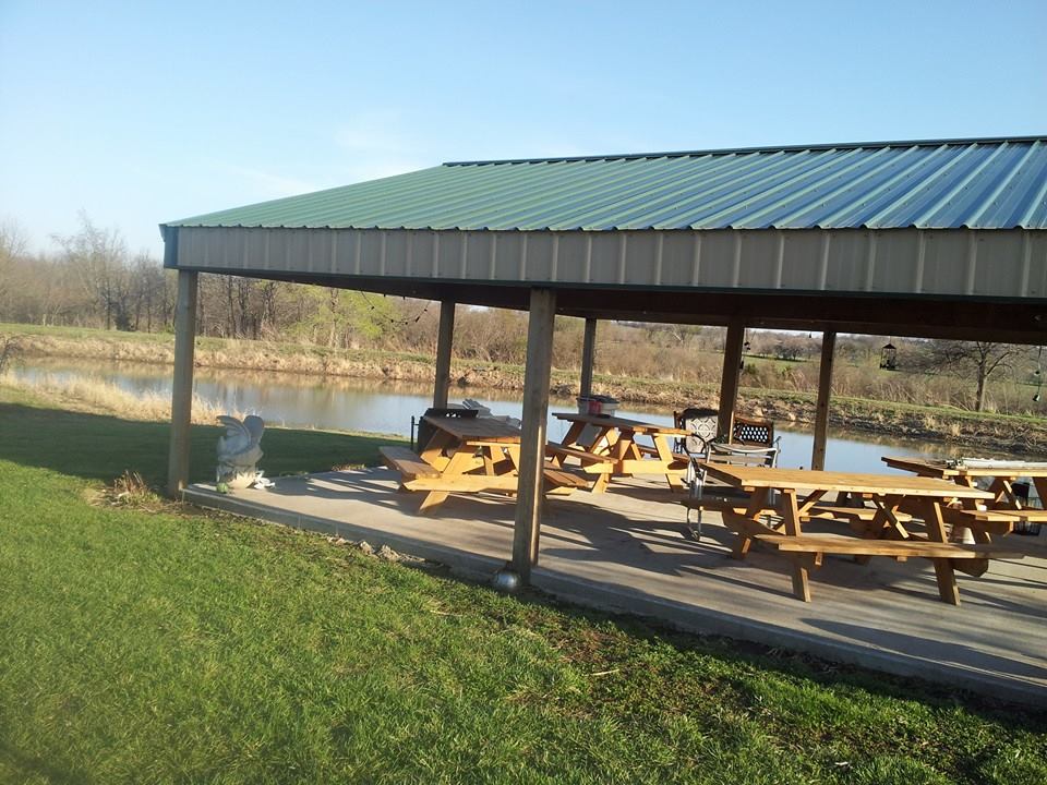 Odessa Country Winery- Pavilion with several picnic tables and chairs. A small pond is in the background.