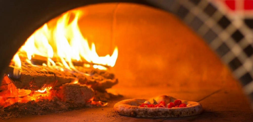Viandel Vineyard- Pizza being cooked inside a pizza oven with an active fire.