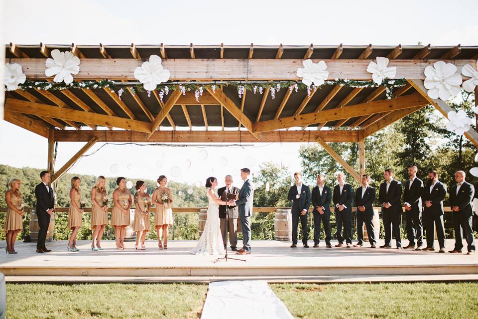 Shawnee Bluff Vineyard - outdoor photo, daytime. A large wooden gazebo is full of people during a wedding ceremony.