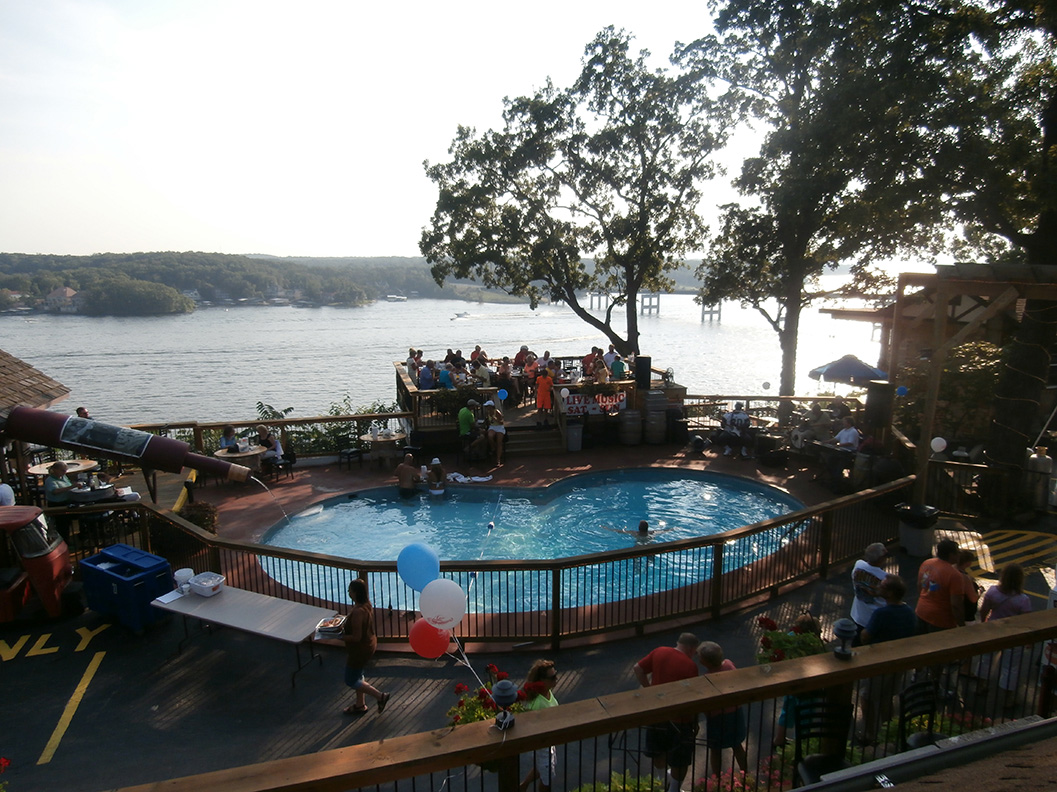 Shawnee Bluff Winery - outdoor photo, daytime, of a large pool surrounded by a large wooden deck. A large body of water and woods are in the background.