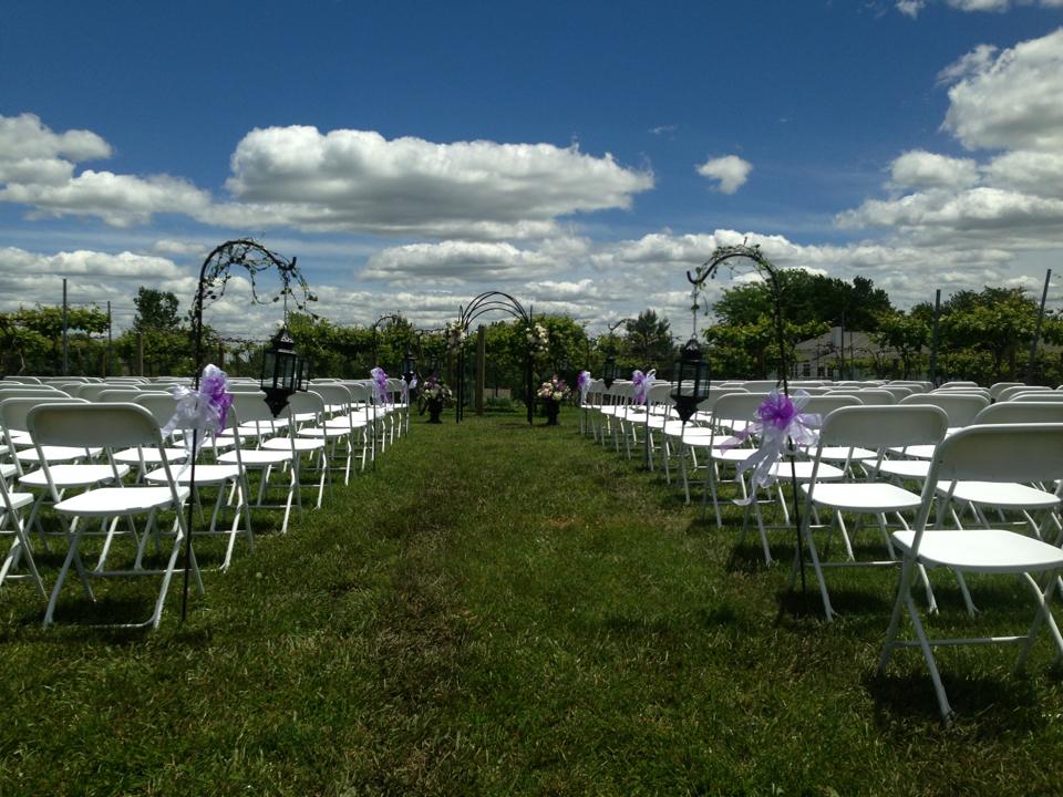 Stonehaus Farms Vineyard & Winery - outdoor photo, daytime, of a flat green field with rows of chairs and an arch, a set up for a wedding.