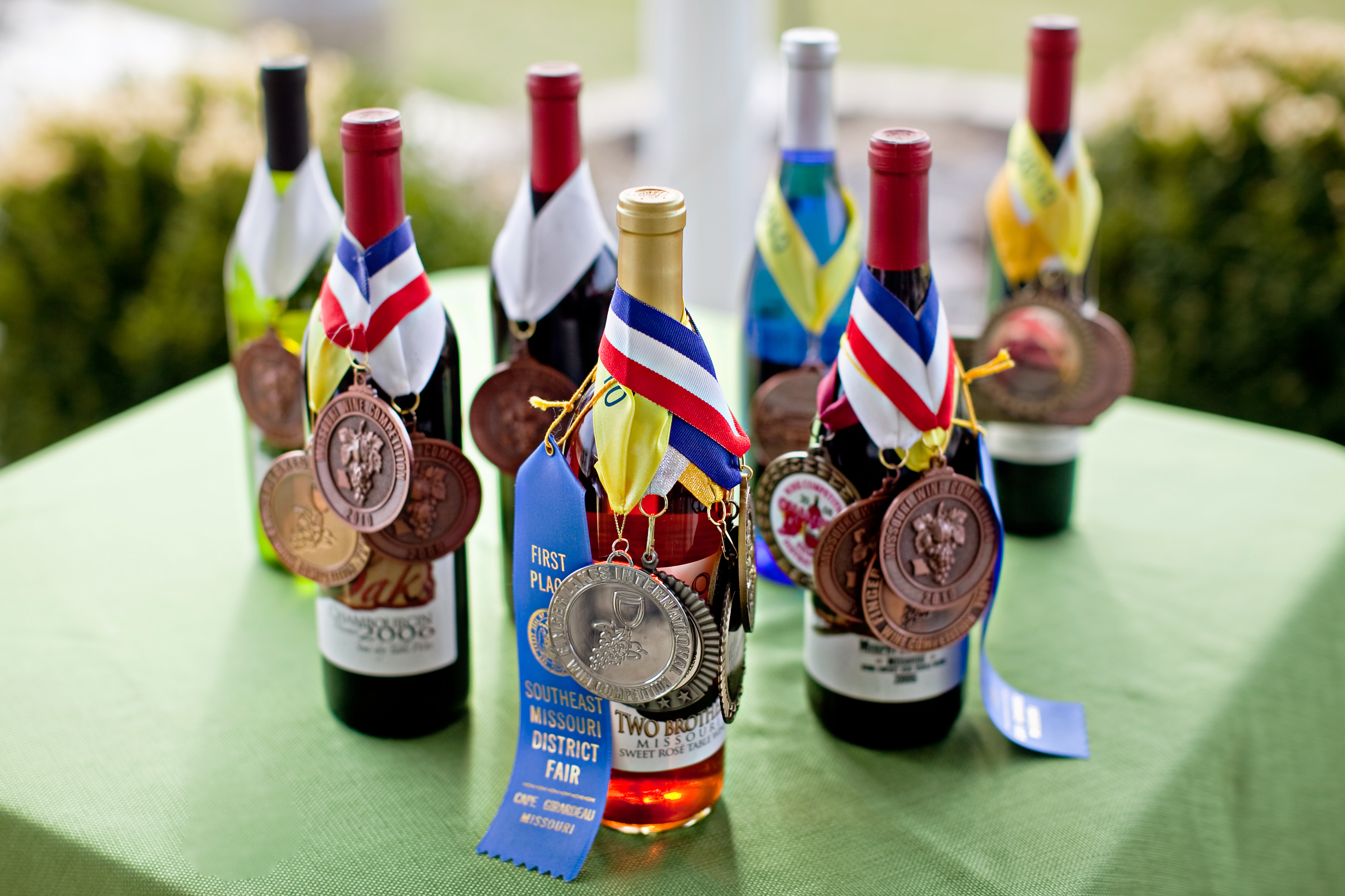 Twin Oaks Vineyard and Winery - outdoor photo, daytime, of several wine bottles arranged on a table with various medals.