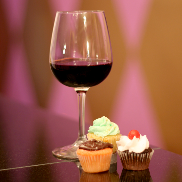 Weston Wine Company- A glass of red wine with three cupcakes.