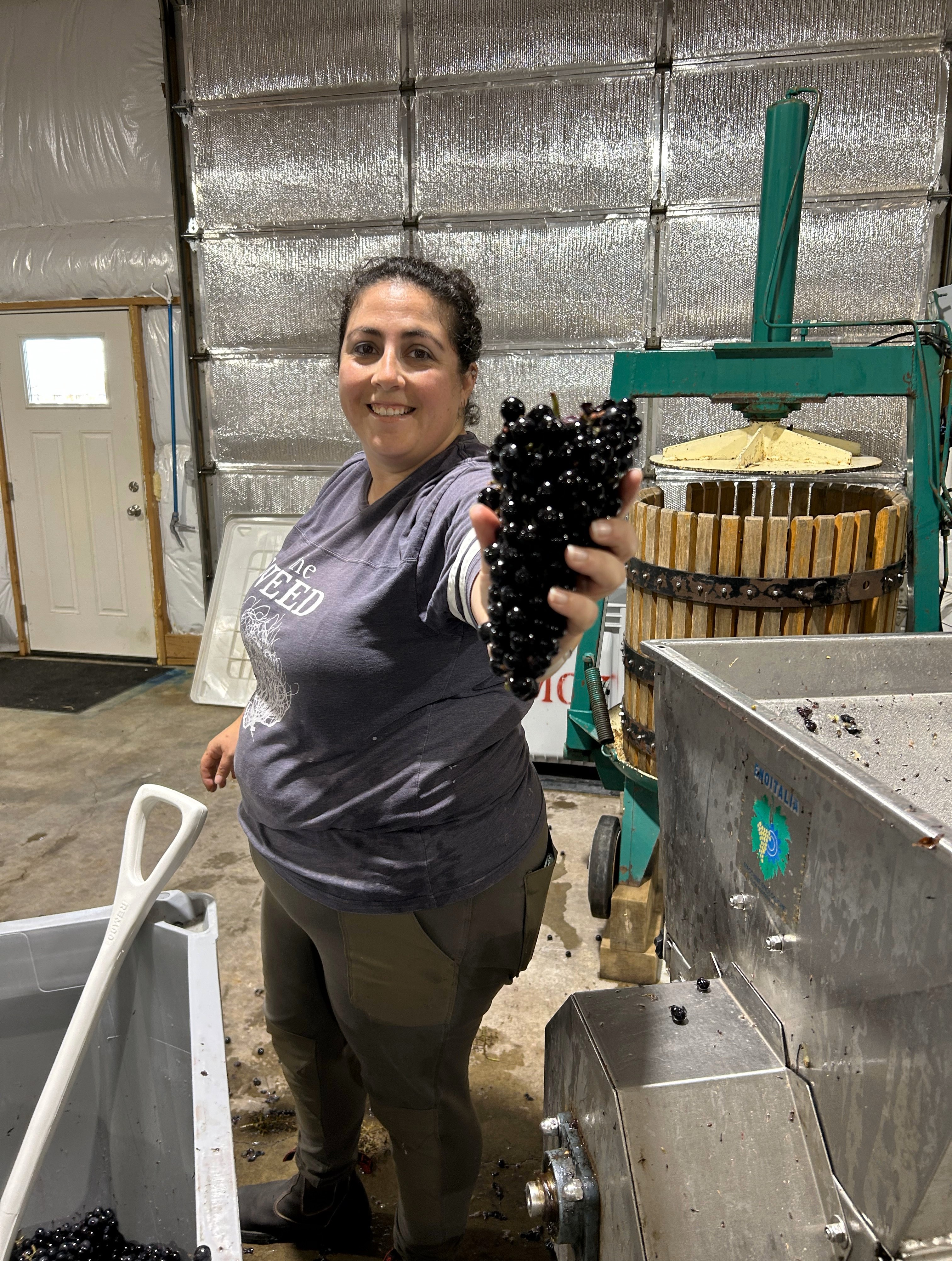 Kim Musket holding a cluster of grapes up to the camera