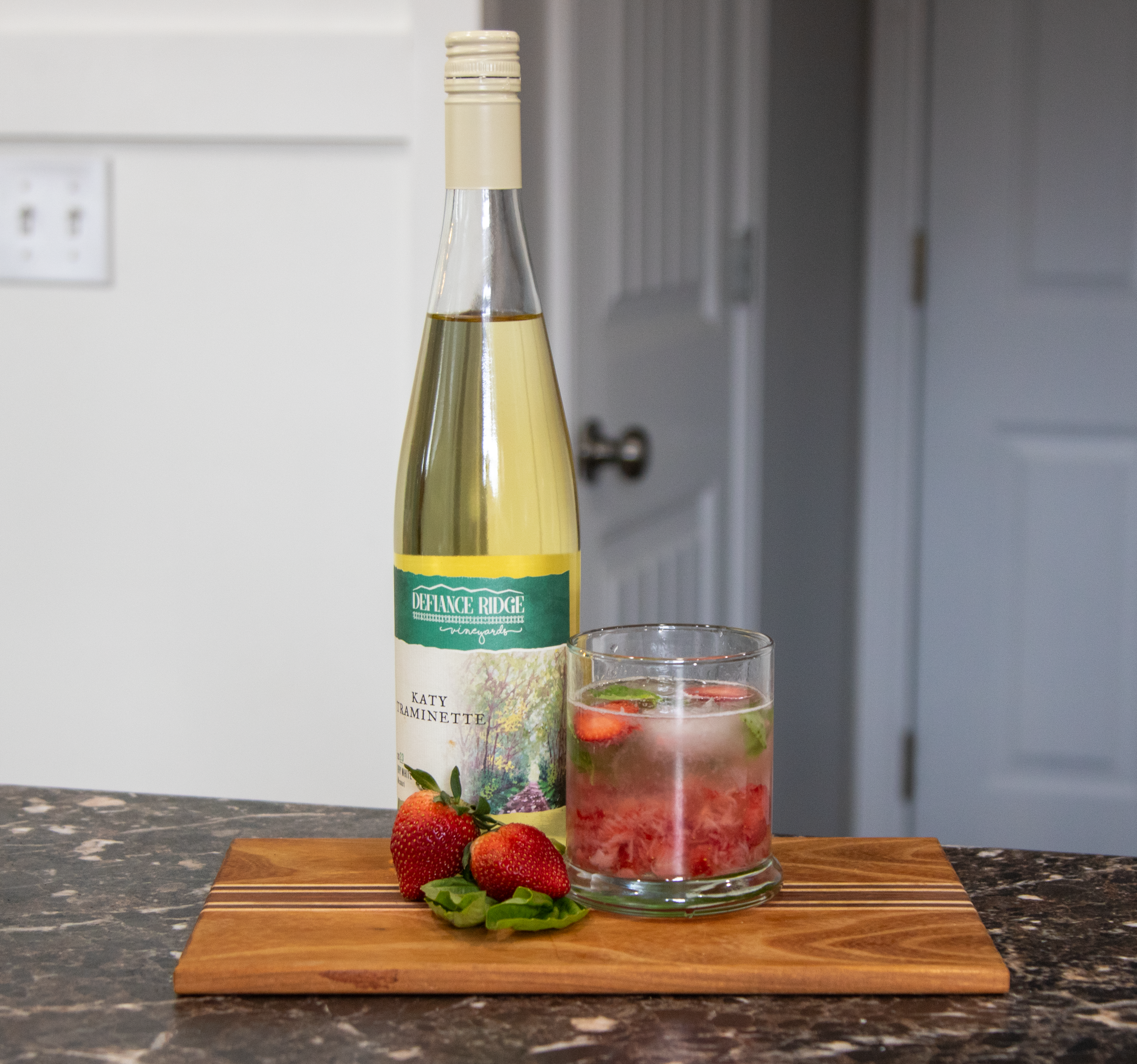 Finished Strawberry Basil Spritzer with wine bottle and strawberries.