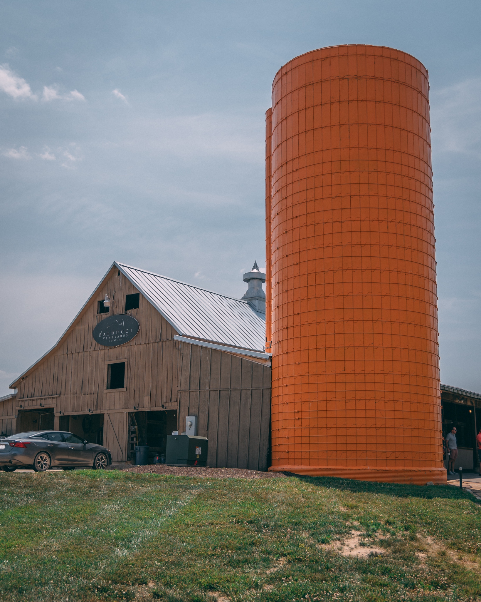 Balducci barn sitting on top of a hill with an orange silo next to it