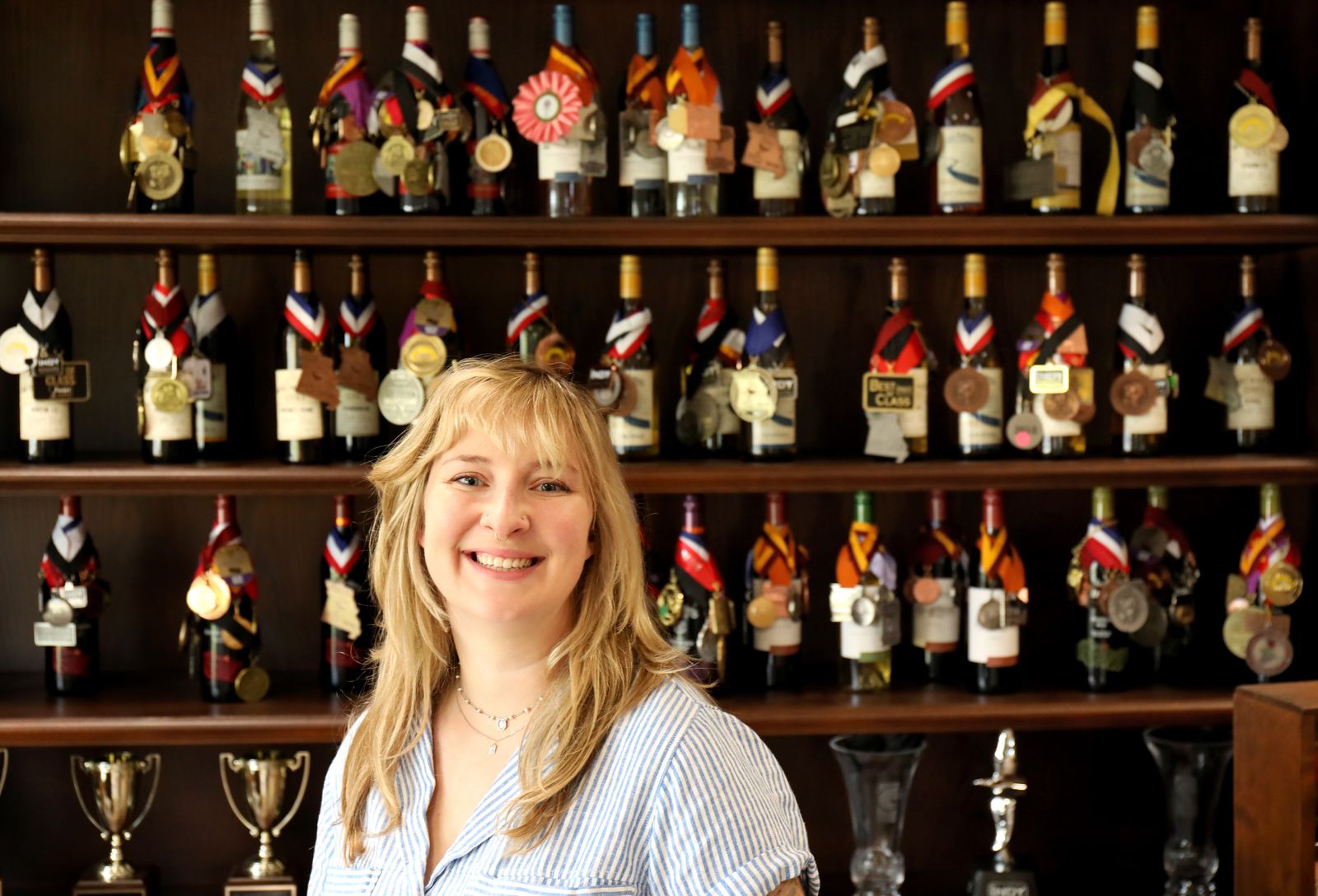 Photo of Brandon Hofherr in front of medals on wine bottles