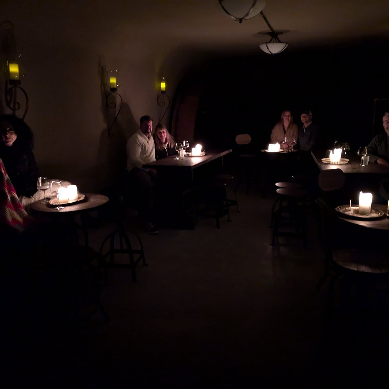 dark room with people sitting by candle light enjoying wine