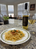 spicy lemon garlic shrimp pasta sitting on a plate with a bottle of wine