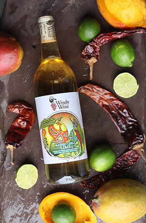 Windy Wine Company- Bottle of Mango Chilli Wine wine laying flat on a brown surface.