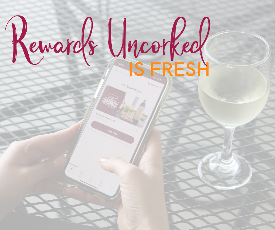 hands holding a phone checking into rewards uncorked with a glass of wine on the table next to them